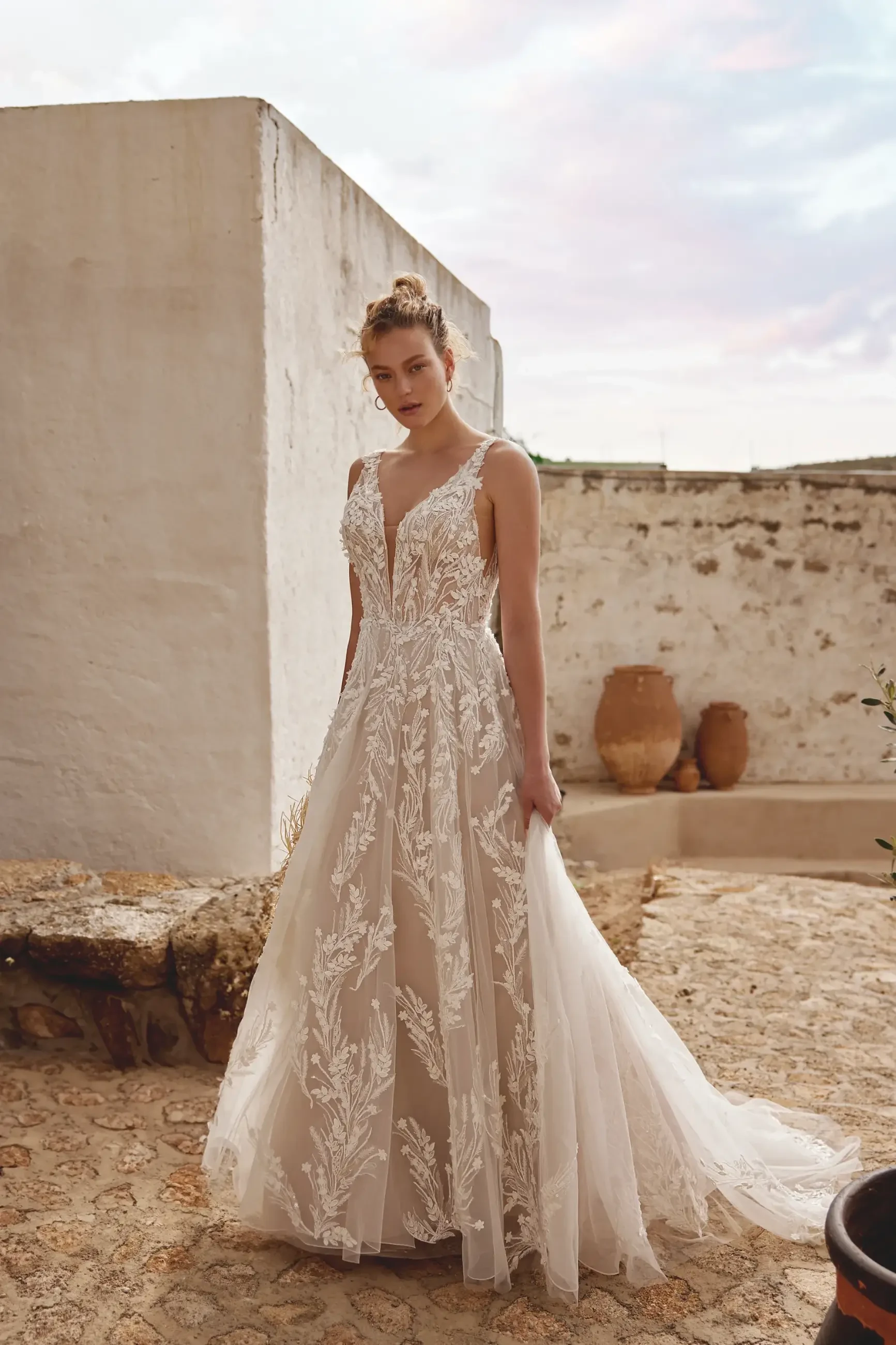 Model is wearing a sleeveless a-line wedding dress with a v-neckline