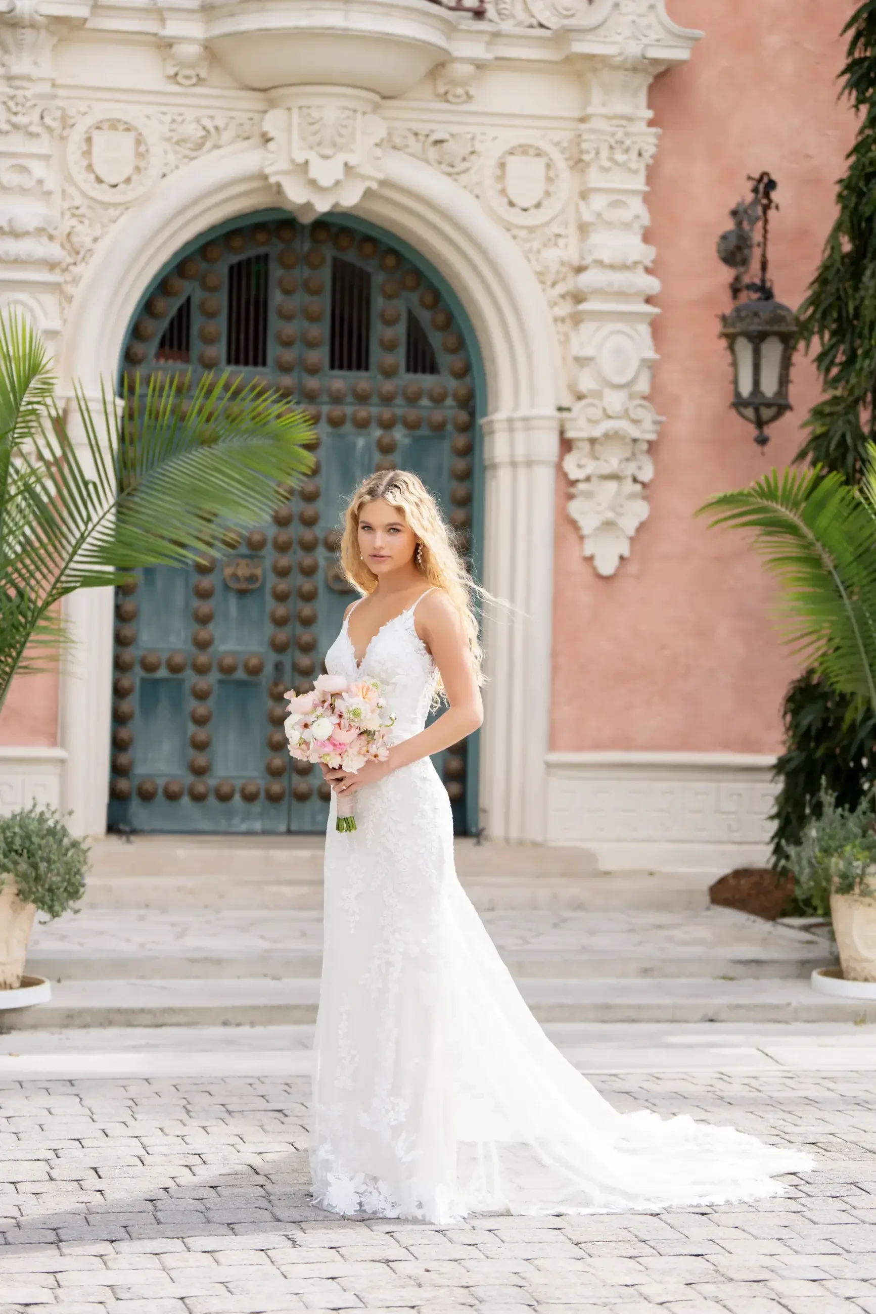 Model is wearing a sheath gown with delicate spaghetti straps, beaded and sequin lace appliques layered over lace and sparkle netting, and a flattering natural waistline.