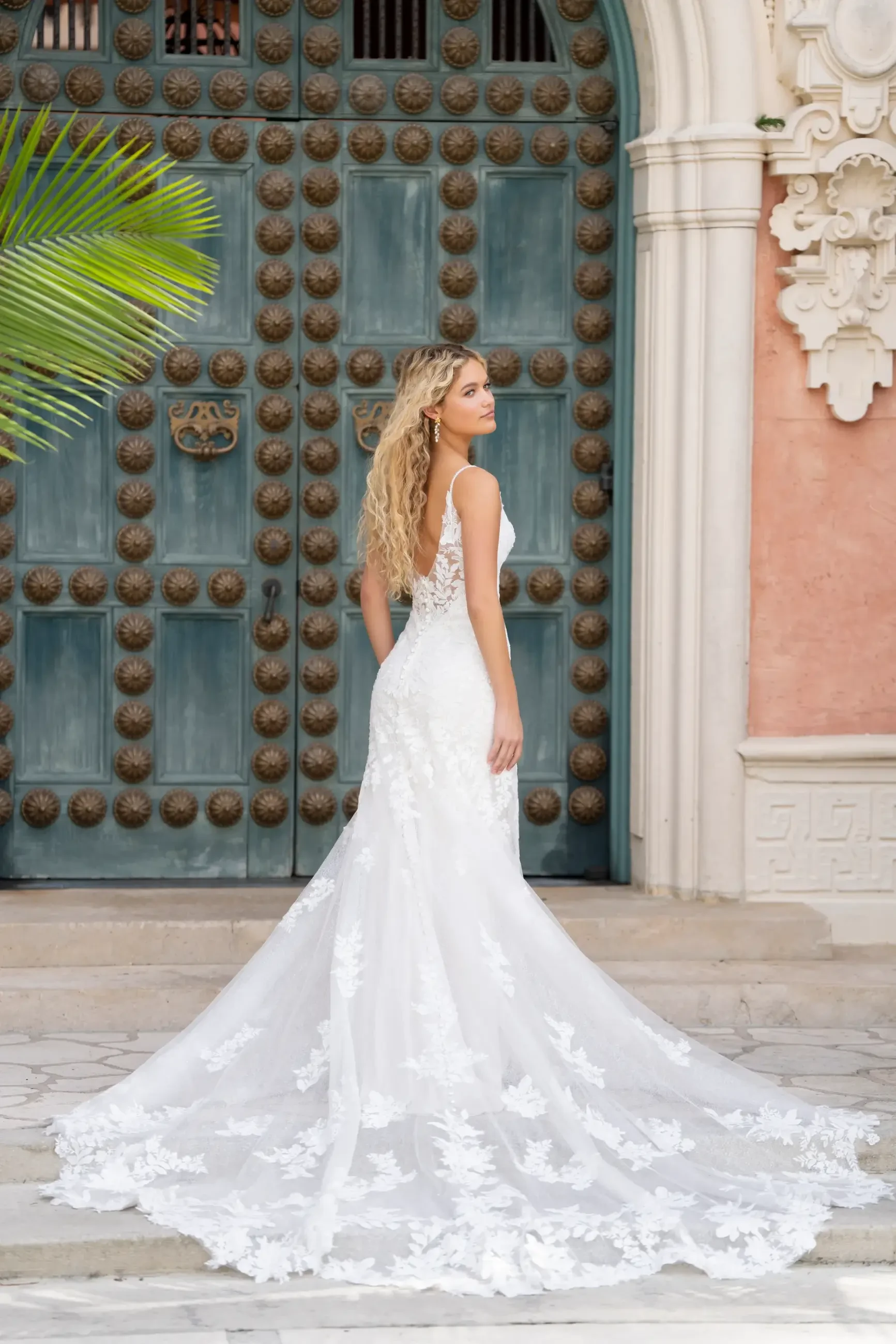 Model is wearing a sheath gown with delicate spaghetti straps, beaded and sequin lace appliques layered over lace and sparkle netting, and a flattering natural waistline.